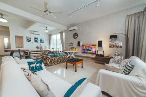 a living room with white couches and a tv at d'Fun 5BR16-24px Pool BBQ NetFlx HotPot KTV Mahjong by Our Stay in Ulu Tiram
