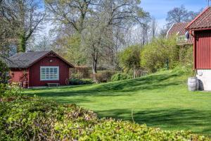 a red barn with a grassy yard next to a building at Bed & Breakfast Holiday House in Nynäshamn