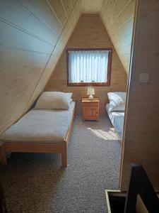a attic bedroom with two beds and a window at Domek u Marty in Solina +15 photos