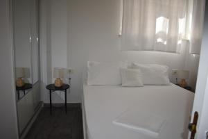 a white bedroom with a bed with white sheets and pillows at CoCo Villa in Makarska