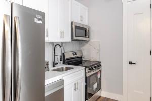 a kitchen with white cabinets and a stainless steel refrigerator at Blueground Midtown West washerdryer nr Central Park NYC-1877 in New York +10 photos