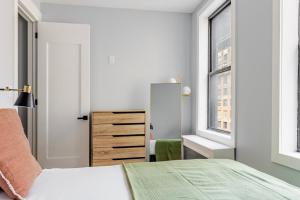 a white bedroom with a bed and a mirror at Blueground Midtown West washerdryer nr Central Park NYC-1877 in New York