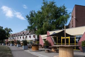 a row of tables and benches on a street with buildings at Auberge de Jeunesse HI Strasbourg 2 Rives in Strasbourg