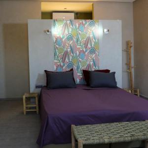 ein Schlafzimmer mit einem lila Bett mit einer farbenfrohen Wand in der Unterkunft Belgium Camp & Rooms jbilat Marrakesh 