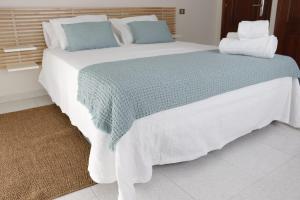 a large bed with blue and white blankets and pillows at Hotel Alejandrina Poio in Poio +22 photos