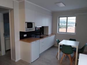 a kitchen with a table and a table and chairs at Apartamentos do Lameirinho in Angra do Heroísmo