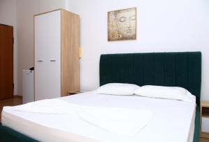 ドゥラスにあるApartel City Center 1の緑のヘッドボードが付いた大きなベッドのある寝室
