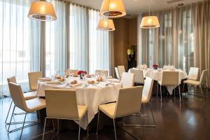 a dining room with white tables and chairs and windows at Hotel Diagonal Plaza in Zaragoza +122 photos
