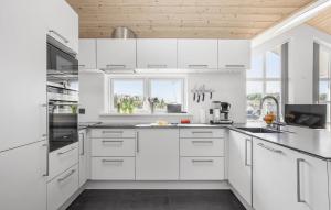 a white kitchen with white cabinets and a window at Four-Bedroom Holiday Home In Rudkobing in Spodsbjerg