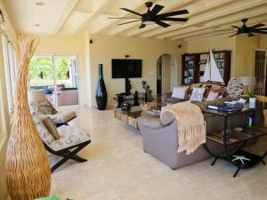 a living room with a couch and a ceiling fan at Villa Luminara- Lux Pool, Garden, Retreat & Beach in Oyster Pond