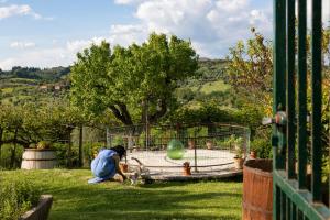 a person playing with a dog in the grass at Borgo Villa Certano - Case Vacanza in Toscana in Siena