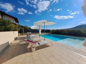 a swimming pool with two lounge chairs and an umbrella at Villa dell'Olivo Bianco in Castion Veronese