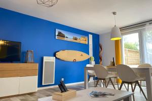 a living room with a blue wall with a surfboard on the wall at Villa Portugal - Domaine Le Sherwood in Notre-Dame-de-Monts +3 photos