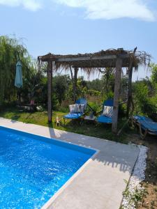 a pool with a gazebo and two chairs next to it at Olive and Blue Retreat in Halikounas