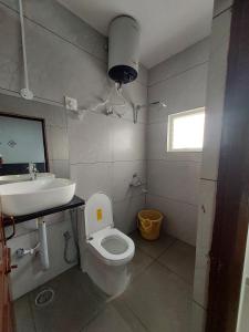 a bathroom with a white toilet and a sink at Nandan Suits in Mysore +54 photos