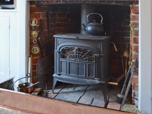 - un vieux poêle noir dans une cheminée en briques dans l'établissement Bow Cottage, à Fordwich