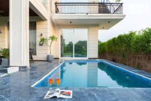 una piscina en el patio trasero de una casa en StayVista at Olive Farms with Lawn, Pool, Bonfire & Hill Views, en Mandkaula