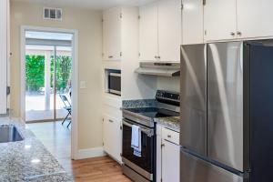 a kitchen with a stainless steel refrigerator and white cabinets at Pet & Family-Friendly 4BR Grill & Chill in Sacramento