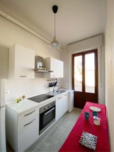 a kitchen with white cabinets and a red table at Comodo e Pratico nel Cuore pulsante di Pisa in Pisa