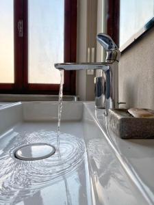 a kitchen sink with water running from a faucet at Comodo e Pratico nel Cuore pulsante di Pisa in Pisa