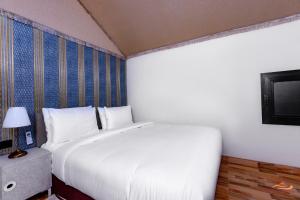 a bedroom with a large white bed and a tv at Desert Rose Village in Al Khatim