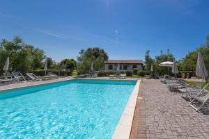 ein Swimmingpool mit Stühlen und Sonnenschirmen in der Unterkunft Agriturismo Gli Etruschi in Populonia