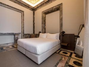 Un dormitorio con una cama blanca y una chimenea en Mercer Residences Sevilla, en Sevilla