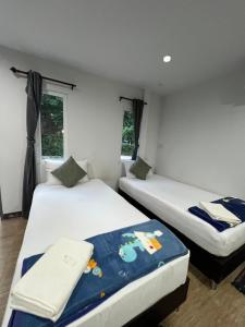 two twin beds in a room with windows at รุ่งเรืองรีสอร์ท3 in Khon Kaen