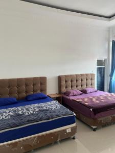 2 Betten in einem Schlafzimmer mit lila Bettwäsche in der Unterkunft RUMAH 25 SYARIAH in Bukittinggi