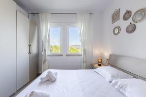 a white bedroom with a white bed and a window at Velipoja Beach Apartment in Velipojë