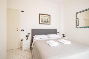 a white bedroom with a bed with two towels on it at Marty Sweet Home, Cattolica Centro in Cattolica