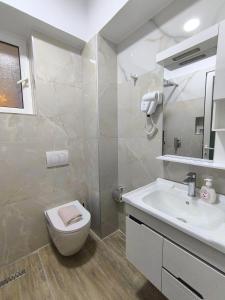 a white bathroom with a toilet and a sink at MD Luxury Studios in Himare +11 photos