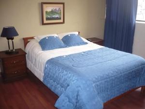 a bedroom with a large bed with a blue blanket at Hostal Tutamanda 2 in Quito