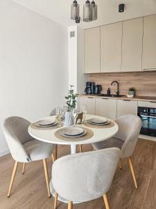a white table with chairs and a white kitchen at Kairos Apartments -Aramis- darmowy parking, klimatyzacja in Olsztynek