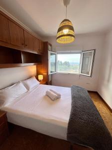 Un dormitorio con una gran cama blanca con una gran ventana. en La Ponderosa, en Castañeras