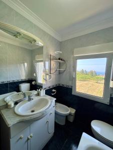 Un baño con lavabo, inodoro y ventana. en La Ponderosa, en Castañeras