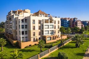 a large white building with palm trees and buildings at Los Pelicanos by Ĥ - Playa Punta del Moral PLHC39P38 in Isla del Moral
