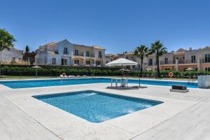 ein Swimmingpool mit Sonnenschirm und einigen Gebäuden in der Unterkunft Vista Hermosa by H - Costa Esuri EVHH167P00 in Ayamonte