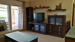 ein Wohnzimmer mit einem TV und einem Entertainment-Center in der Unterkunft Las Marismas by Ĥ - Isla Canela Golf GLHM117P134 in Isla Canela