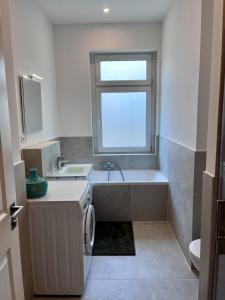 a bathroom with a tub and a sink and a washing machine at Zur Kaiserin - im Süden Berlins in Berlin +11 photos