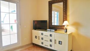 a room with a dresser with a television and a mirror at Marina III by Ĥ - Marina Isla Canela PMHIII12P13 in Isla del Moral