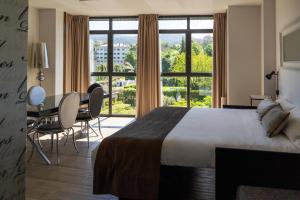 pokój hotelowy z łóżkiem, stołem i krzesłami w obiekcie Alvear Suites w mieście Redondela
