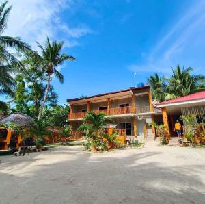 a building with palm trees in front of it at MARIA GUEST House in Maricaban