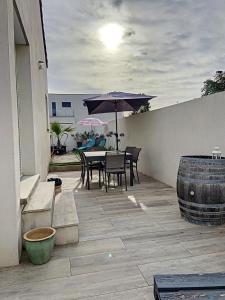 a patio with an umbrella and a table and chairs at Villa Harmony Climatisation Piscine semi enterrée Wifi Camargue in Saint-Just +22 photos