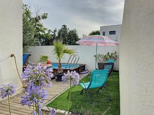 a patio with a table and chairs and an umbrella at Villa Harmony Climatisation Piscine semi enterrée Wifi Camargue in Saint-Just