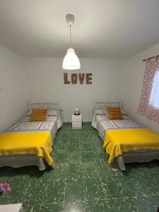 two beds in a room with love sign on the wall at Casita Rural La Rosa de la Huerta con chimenea interior in Monachil +52 photos