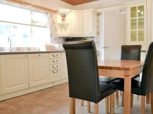 a kitchen with a wooden table and black chairs at Blackmoor Farmhouse in Stepaside
