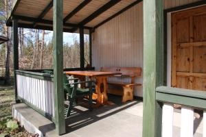 eine Veranda mit einem Holztisch und einer Bank in der Unterkunft Domek Weranda in Tleń