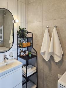 une salle de bain avec un lavabo, un miroir et des serviettes dans l'établissement Kairos Apartments -Atos - darmowy parking, klimatyzacja, à Olsztynek