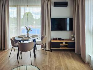 un salon avec une table, des chaises et une télévision dans l'établissement Kairos Apartments -Atos - darmowy parking, klimatyzacja, à Olsztynek 28 autres photos